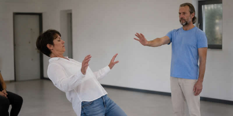 Real no touch body reaction demonstration with a woman losing balance while a man focuses intention without physical contact.